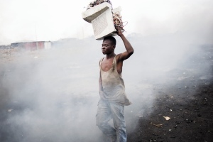 Junger Mann in Ghana beim Verbrennen von Elektroschrott
